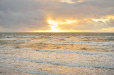 Gün batımında Baltık kıyılarından panoramik manzara. Dramatik bulutlar, parlayan bulutlar, fırtınadan sonra altın güneş ışığı. Doğa, çevre, iklim değişikliği, kararsız hava