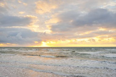 Gün batımında Baltık kıyılarından panoramik manzara. Dramatik bulutlar, parlayan bulutlar, fırtınadan sonra altın güneş ışığı. Doğa, çevre, iklim değişikliği, kararsız hava