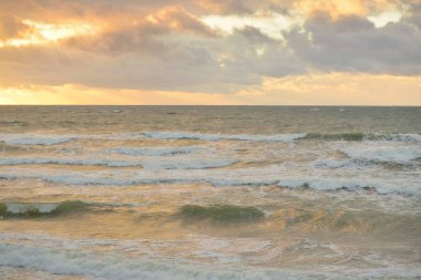 Gün batımında Baltık kıyılarından panoramik manzara. Dramatik bulutlar, parlayan bulutlar, fırtınadan sonra altın güneş ışığı. Doğa, çevre, iklim değişikliği, kararsız hava