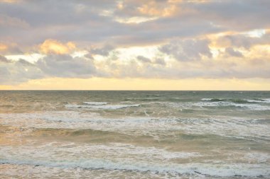Gün batımında Baltık kıyılarından panoramik manzara. Dramatik bulutlar, parlayan bulutlar, fırtınadan sonra altın güneş ışığı. Doğa, çevre, iklim değişikliği, kararsız hava