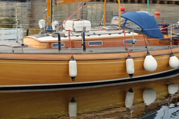 Modern klasik ahşap İsveçli yelkenli teknesi yat limanındaki bir iskeleye demirlemiş. Turizm, tatiller, boş zaman aktiviteleri, eğlence, yelkencilik temaları