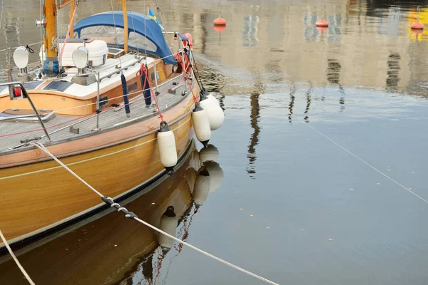 Modern klasik ahşap İsveçli yelkenli teknesi yat limanındaki bir iskeleye demirlemiş. Turizm, tatiller, boş zaman aktiviteleri, eğlence, yelkencilik temaları