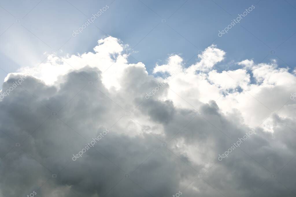 Coudscape. White ornamental clouds. Soft sunlight, sunbeams. Clear blue sky. Natural pattern, texture, background, wallpaper, graphic resources, design, copy space. Symbol of peace