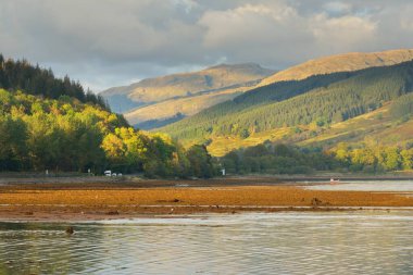 Kayalık göl kıyıları, dağlar, orman. İskoçya, İngiltere. Atmosferik manzara. Seyahat merkezleri, eko turizm, yürüyüş, doğa, çevre koruma