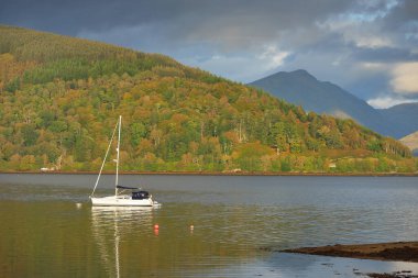 Yelkenli göle demir attı. Görkemli orman tepeleri. İskoçya, İngiltere. Atmosferik manzara. Seyahat yerleri, yelkencilik, seyir, eko turizm, yürüyüş, doğa, çevre koruma