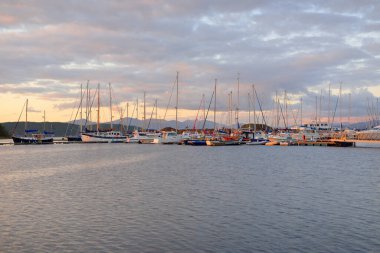 Günbatımında yat limanında demirlemiş zarif ve modern yelkenliler. Dramatik bulutlar. Inner Hebrides, İskoçya, İngiltere. Ulaşım, spor, yelkencilik, eğlence, eğlence, eğlence, gezi, turizm