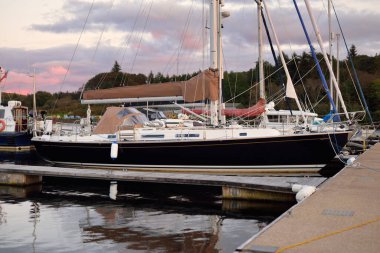 Günbatımında yat limanında demirlemiş zarif ve modern yelkenliler. Dramatik bulutlar. Inner Hebrides, İskoçya, İngiltere. Ulaşım, spor, yelkencilik, eğlence, eğlence, eğlence, gezi, turizm