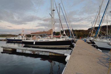 Günbatımında yat limanında demirlemiş zarif ve modern yelkenliler. Dramatik bulutlar. Inner Hebrides, İskoçya, İngiltere. Ulaşım, spor, yelkencilik, eğlence, eğlence, eğlence, gezi, turizm