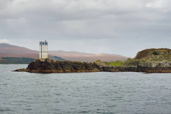 Rocky gölü kıyıları, dağ zirveleri, dağlar, vadiler ve tepeler. Deniz feneri. Yelkenliden panoramik manzara. Dramatik bir gökyüzü. İskoçya, İngiltere. Atmosferik manzara. Seyahat yerleri, yürüyüş, eko-turizm