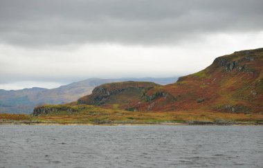 İskoçya, Rothesay 'ın kayalık kıyıları, tepeleri ve vadileri üzerinde dramatik bir gökyüzü. Yelkenliden panoramik manzara. Seyahat merkezleri, turizm, yürüyüş, dönüm noktası, ekoloji, çevre, doğa temaları