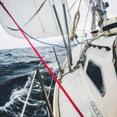 Gün batımında açık denizde yelken açmak. Güverteden pruvaya, direğe ve yelkenlere yakın görüntü. Dramatik gökyüzü, dalgalar, kasırga, sert hava. Destansı deniz manzarası
