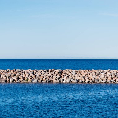 Gün batımında Baltık kıyısı manzarası. Gökyüzü açık. Dalgalar ve su sıçramaları. Idyllic deniz manzarası. Ruhnu Adası, Estonya