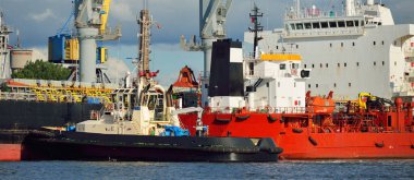 Kargo gemileri iskele terminaline yükleniyor. Vinçler arka planda. Baltık Denizi. Bunkering, akaryakıt ve enerji üretimi, arz, teknoloji, lojistik, hizmet, sanayi, ticaret