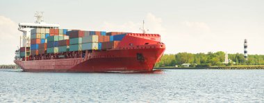 Konteyner gemisi (168 metre uzunluğunda) gün batımında limandan ayrılıyor. Baltık Denizi. Yük taşımacılığı, lojistik, küresel iletişim, dünya çapında taşımacılık, ekonomi, iş dünyası, sanayi