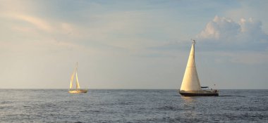Baltık Denizi 'nde yelkenli bir yat. Gün batımı. Fırtınadan sonra dramatik bir gökyüzü, yumuşak güneş ışığı. Ulaşım, seyahat, seyahat, yat yarışı, spor, eğlence, eğlence, eğlence, yaşam tarzı, aile.