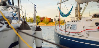 Yelkenliler açık bir yaz gününde yat limanındaki bir rıhtıma demirlediler. Tekne çamurlukları yakın plan. Ekipman, ulaşım, eğlence, tatil, boş zaman aktivitesi, spor, gezi, yaşam tarzı