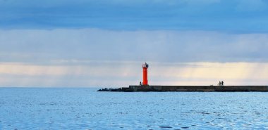 Güneş pilli deniz feneri. Baltık Denizi. Fırtınadan sonra dramatik günbatımı gökyüzü. Parlayan bulutlar, altın güneş ışığı. Umut ve barışın sembolü. Mimarlık, seyahat yerleri, navigasyon, yelkencilik.