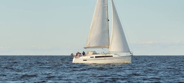 Baltık Denizi 'nde yelkenli bir yat. Gün batımı. Fırtınadan sonra dramatik bir gökyüzü, yumuşak güneş ışığı. Ulaşım, seyahat, seyahat, yat yarışı, spor, eğlence, eğlence, eğlence, yaşam tarzı, aile.