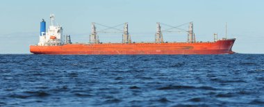 Büyük kırmızı bir yük gemisi (179 metre uzunluğunda) açık bir Baltık Denizi 'nde yüzüyor. Dramatik bir gökyüzü. Yük taşımacılığı, denizcilik gemisi, lojistik, küresel iletişim, ekonomi, iş dünyası, sanayi