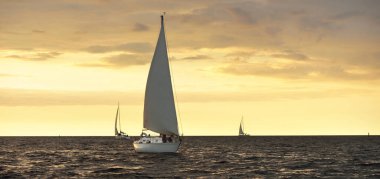 Baltık Denizi 'nde yelkenli bir yat. Gün batımı. Fırtınadan sonra dramatik bir gökyüzü, altın güneş ışığı. Ulaşım, seyahat, gezi, yat yarışı, spor, eğlence, boş zaman aktivitesi, yaşam tarzı