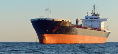 Büyük bir kargo gemisi (kimyasal tanker, 184 metre uzunluğunda) gün batımında açık denizde yol alır. Altın güneş ışığı. Yük taşımacılığı, yakıt, enerji üretimi, denizcilik gemisi, lojistik, ekonomi, sanayi
