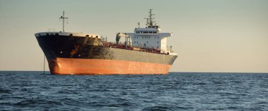 Büyük bir kargo gemisi (kimyasal tanker, 184 metre uzunluğunda) gün batımında açık denizde yol alır. Altın güneş ışığı. Yük taşımacılığı, yakıt, enerji üretimi, denizcilik gemisi, lojistik, ekonomi, sanayi