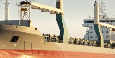 Büyük vinç gemisi (genel yük, 146 metre uzunluğunda) gün batımında açık denizde yol alır. Altın güneş ışığı. Yük taşımacılığı, lojistik, küresel iletişim, ekonomi, sanayi, dünya çapında taşımacılık