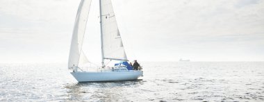 Açık denizde yelkenli yelkenli yelkenli. Gökyüzü açık, bulutlu. Yelkenlinin manzarası. Ulaşım, seyahat, spor, eğlence, boş zaman aktivitesi, yarış, yelkenli yarışı. Panorama, boşluğu kopyala