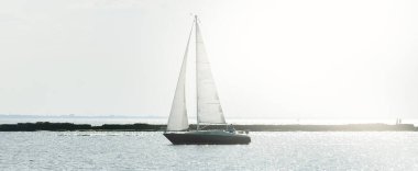 Günbatımında Baltık Denizi 'nde yelkenli yelkenli yelkenli. Fırtınadan sonra açık gökyüzü, yumuşak güneş ışığı. Deniz feneri. Ulaşım, seyahat, gezi, spor, eğlence, boş zaman aktivitesi, yarış, yelkenli yarışı