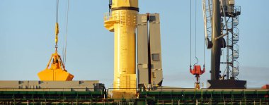 Liman terminalinde vinçleri yükleyen büyük bir yük gemisi (179 metre uzunluğunda). Baltık Denizi. Nakliye, lojistik, küresel iletişim, ekonomi, ticaret, sanayi, arz