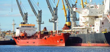 Kargo gemileri iskele terminaline yükleniyor. Vinçler arka planda. Baltık Denizi. Bunkering, akaryakıt ve enerji üretimi, arz, teknoloji, lojistik, hizmet, sanayi, ticaret