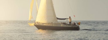 Baltık Denizi 'nde yelkenli bir yat. Gün batımı. Fırtınadan sonra dramatik bir gökyüzü, yumuşak güneş ışığı. Ulaşım, seyahat, seyahat, yat yarışı, spor, eğlence, eğlence, eğlence, yaşam tarzı, aile.