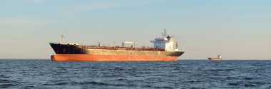 Büyük bir kargo gemisi (kimyasal tanker, 184 metre uzunluğunda) gün batımında açık denizde yol alır. Altın güneş ışığı. Yük taşımacılığı, yakıt, enerji üretimi, denizcilik gemisi, lojistik, ekonomi, sanayi