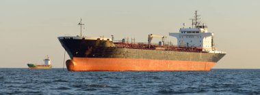 Büyük bir kargo gemisi (kimyasal tanker, 184 metre uzunluğunda) gün batımında açık denizde yol alır. Altın güneş ışığı. Yük taşımacılığı, yakıt, enerji üretimi, denizcilik gemisi, lojistik, ekonomi, sanayi