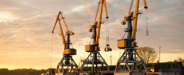 Riga, Letonya 'daki modern kargo limanı terminali. Vinçler yakın plan. Dramatik bir gökyüzü. Baltık Denizi. Yük taşımacılığı, lojistik, küresel iletişim, ekonomi, ticaret, sanayi, arz, özel ekipman