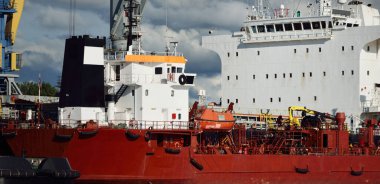 Kargo gemileri iskele terminaline yükleniyor. Vinçler arka planda. Baltık Denizi. Bunkering, akaryakıt ve enerji üretimi, arz, teknoloji, lojistik, hizmet, sanayi, ticaret