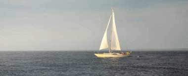 Baltık Denizi 'nde yelkenli bir yat. Gün batımı. Fırtınadan sonra dramatik bir gökyüzü, yumuşak güneş ışığı. Ulaşım, seyahat, seyahat, yat yarışı, spor, eğlence, eğlence, eğlence, yaşam tarzı, aile.