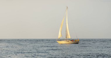 Baltık Denizi 'nde yelkenli bir yat. Gün batımı. Fırtınadan sonra dramatik bir gökyüzü, yumuşak güneş ışığı. Ulaşım, seyahat, seyahat, yat yarışı, spor, eğlence, eğlence, eğlence, yaşam tarzı, aile.