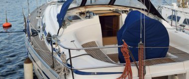 Limandaki bir rıhtıma demirlenmiş modern bir yat. Tahta meşe güvertesinin yukarıdan görünüşü, donanım donanımı. Akdeniz 'de. Kiralık, deniz yolculuğu, eğlence, eğlence, eğlence, spor için özel bir gemi.