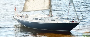 Kumlu kıyıya demirli mavi şalopeli yat (kumsalda otlarla kaplanmış). İsveç 'te, Avrupa' da. Doğa, yaz tatilleri, eğlence, gezi, spor, ulaşım. Hava görünümü