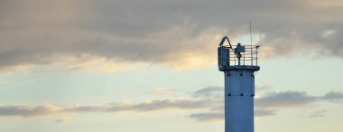 Güneş pilli deniz feneri. Baltık Denizi. Fırtınadan sonra dramatik günbatımı gökyüzü. Parlayan bulutlar, altın güneş ışığı. Umut ve barışın sembolü. Mimarlık, seyahat yerleri, navigasyon, yelkencilik.