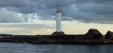 Güneş pilli deniz feneri. Baltık Denizi. Fırtınadan sonra dramatik günbatımı gökyüzü. Parlayan bulutlar, altın güneş ışığı. Umut ve barışın sembolü. Mimarlık, seyahat yerleri, navigasyon, yelkencilik.