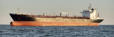 Büyük bir kargo gemisi (kimyasal tanker, 184 metre uzunluğunda) gün batımında açık denizde yol alır. Altın güneş ışığı. Yük taşımacılığı, yakıt, enerji üretimi, denizcilik gemisi, lojistik, ekonomi, sanayi
