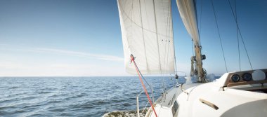 Günbatımında Baltık Denizi 'nde yelkenli yelkenli yelkenli. Kokpitten pruvaya, direğe ve yelkenlere bakın. Ulaşım, seyahat, gezi, spor, eğlence, boş zaman aktivitesi, yelkenli yarışı