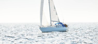 Açık denizde yelkenli yelkenli yelkenli. Gökyüzü açık, bulutlu. Yelkenlinin manzarası. Ulaşım, seyahat, spor, eğlence, boş zaman aktivitesi, yarış, yelkenli yarışı. Panorama, boşluğu kopyala