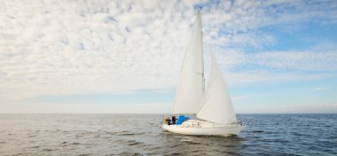 Açık denizde yelkenli yelkenli yelkenli. Gökyüzü açık, bulutlu. Yelkenlinin manzarası. Ulaşım, seyahat, spor, eğlence, boş zaman aktivitesi, yarış, yelkenli yarışı. Panorama, boşluğu kopyala