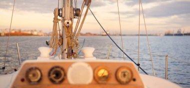 Beyaz yat gün batımında limana varacak. Güverteden pruva ve yelkenlere kadar yakın çekim. Fırtınadan sonra dramatik bir gökyüzü. Baltık Denizi. Deniz aracı, ulaşım, hizmet, spor, eğlence kavramları