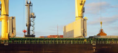 Liman terminalinde vinçleri yükleyen büyük bir yük gemisi (179 metre uzunluğunda). Baltık Denizi. Nakliye, lojistik, küresel iletişim, ekonomi, ticaret, sanayi, arz