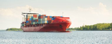 Konteyner gemisi (168 metre uzunluğunda) gün batımında limandan ayrılıyor. Baltık Denizi. Yük taşımacılığı, lojistik, küresel iletişim, dünya çapında taşımacılık, ekonomi, iş dünyası, sanayi