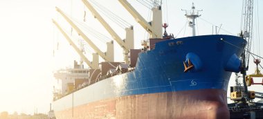 Büyük kargo gemisi (toplu taşıyıcı, 187 metre uzunluğunda) iskele terminalinde yükleme, arka planda vinçler. Yük taşımacılığı, lojistik, küresel iletişim, ekonomi, ticaret, sanayi